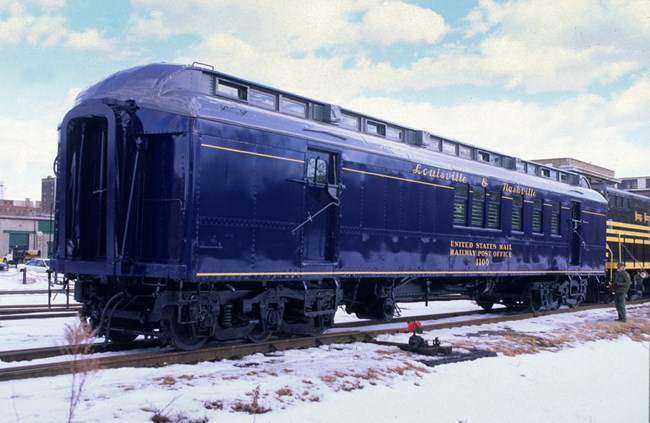A special railroad car, built for the US Post Office's Railway Mail Service, painted bright blue with gold lettering for the Louisville & Nashville Railroad