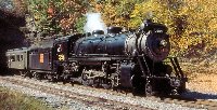 Candian National 3254 rolls out of Nay Aug tunnel pulling a dark green passenger car.&nbsp;