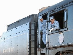 engineer and fireman, wearing traditional hickory strip overalls, jackets and hats, lean out the window of one of Steamtown's steam locomotives.