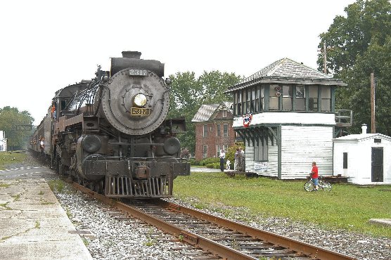 CP 2317, a black steam locomotive, rolls past a white and green railroad tower in East Stroudsburg, PA.