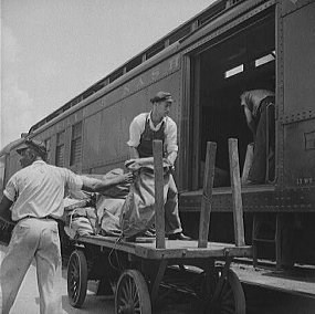 Workers load bags of mail onto a Railway Post Office Car.  Historic Photo