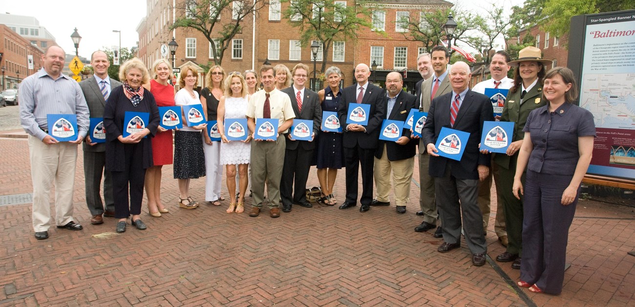 A group of people standing in a line, each holding a small blue sign.
