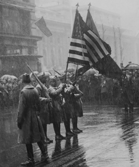 Soldiers holding flags at attention while several others look on all around them