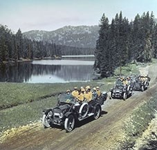 Auto tour passing Sylvan Lake in Yellowstone National Park, 1916. Colored lantern slide by Haynes.