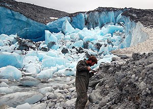 A GeoScientist-in-the-Parks volunteer collects research data in a glacial environment.