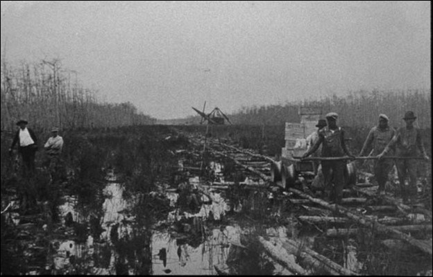 Black and white men laying train track in Big Cypress swamp