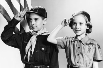 Boy Scout and Girl Scout salute the American flag.
