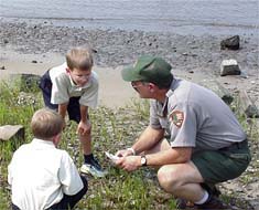 Children and a ranger look at items found along the riverfront.