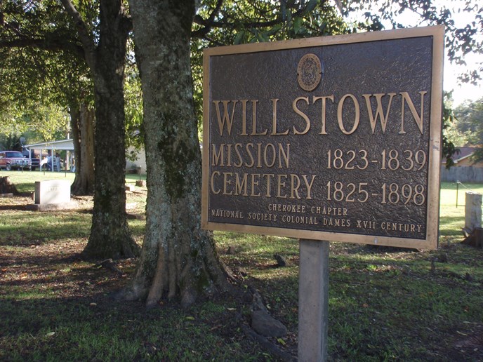 metal sign that says Willstown Mission Cemetery, trees in background