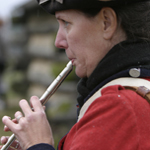 reenactor playing the tin whistle at a living history event