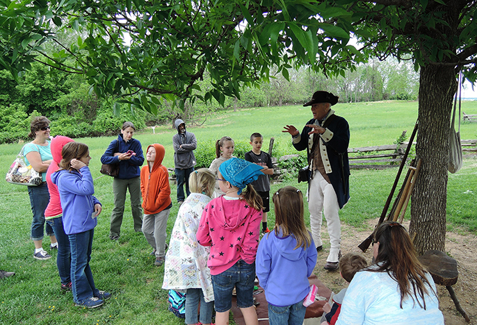 A ranger in Continental Soldier attire tells a story to children.