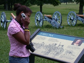 A girl at the Valley Forge artillery park reads a sign while listening to the cell phone tour.