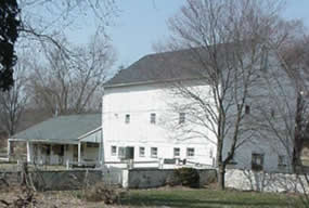 White barn with white fencing and small covered pavilion.