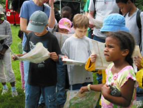 Children listen attentively and examine papers at National Trails Day.