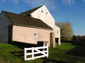 White building with attached barn and white fencing.