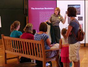 a ranger talks to visitors on the museum floor aout clothes of the 18th century