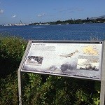 An interpretive exhibit along the water's edge, with the USS Arizona Memorial in the distance.