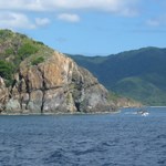 The view is shown from a boat, as it travels past a headland on the island of St. John.  Looking across the water at the cut-away portion of the headland, you can see a geologic sill.