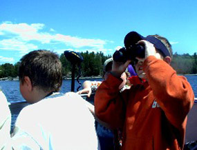 A young visitor looks up through binoculars to search for bald eagles