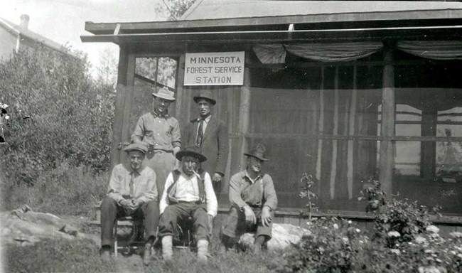 Historic photo of five men sitting in front of a screened in porch of a Minnesota Forest Service Station