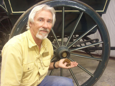 Art Peters holds stage coach wheel nut found in ghost town.