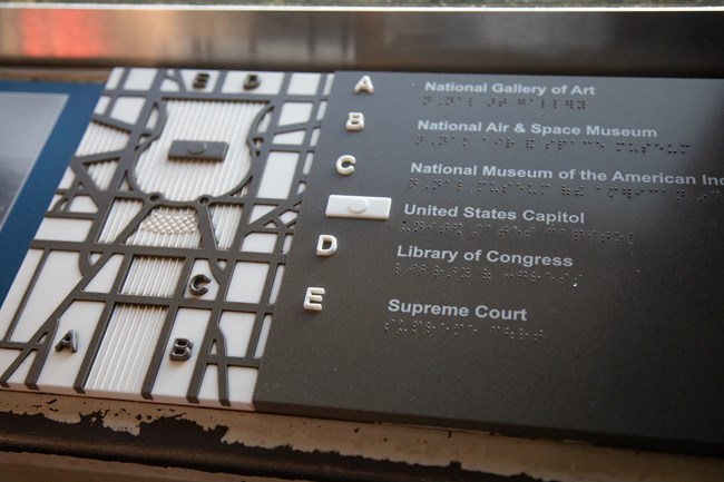 A braille, tactile map shows six prime locations throughout the National Mall using letters to coordinate location.