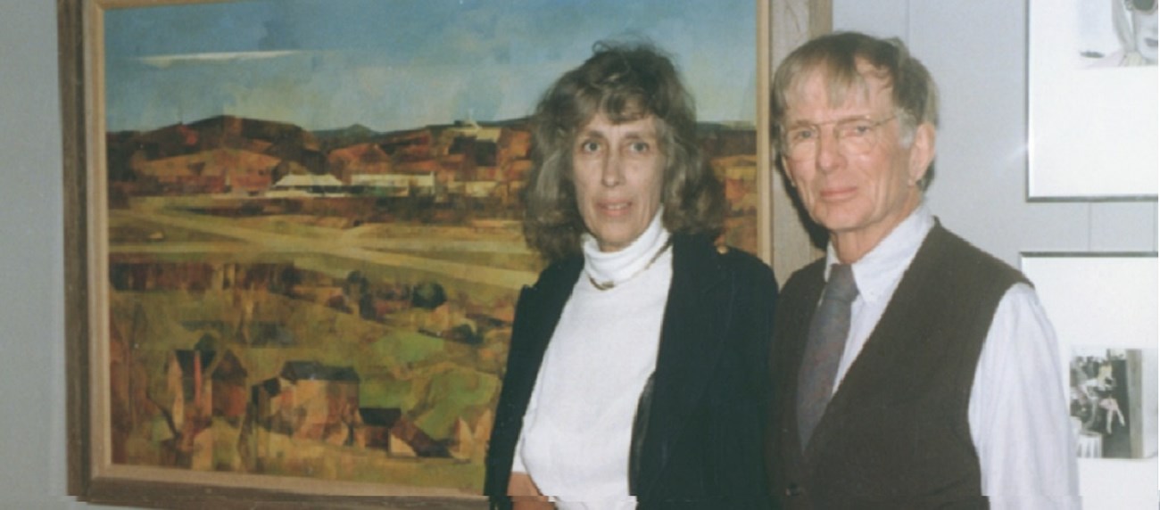 A man and a women standing in front of a painting.