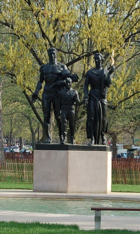 Boy Scout Memorial depicting 3 figures- a man, scout, and woman. Pool in foreground.