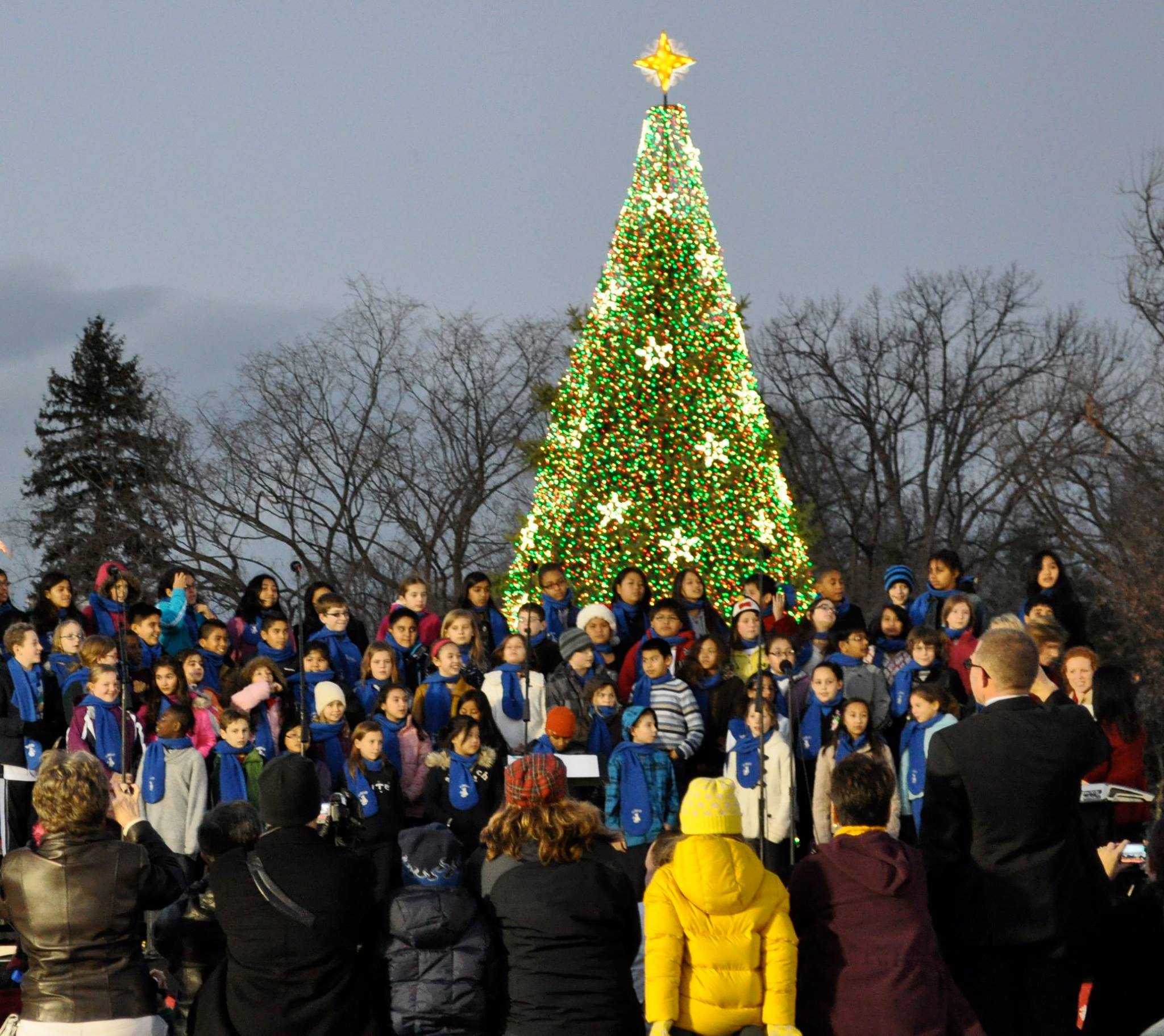 A choir sings in front of the National Christmas Tree, during the 2013 music program, while visitors take pictures