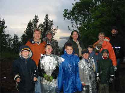 Rain soaked Scouts and adults after completion of Native Plant garden weed picking with lake in background