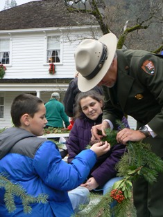 Superintendent Jim Milestone helps a young visitor create a holiday wreath