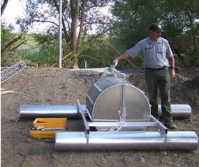 Park employee standing next to pump that will be installed in the stream bed.