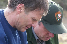 close-up of two men looking down, concentrating on what they are looking at 