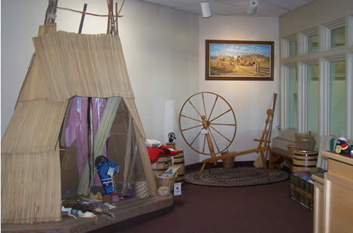 inside of Visitor Center showing a tule mat lodge and a spinnin wheel