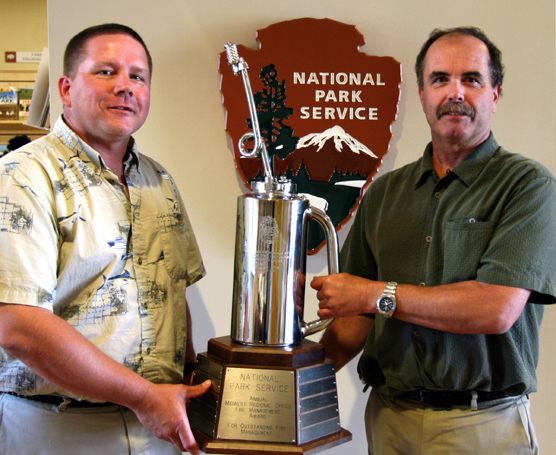 Jim McMahill (left), Fire Management Officer at Wind Cave National Park, accepts  the “drip torch” trophy from Doug Alexander (right), Midwest Region Fire and Aviation Management Officer.