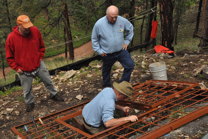 Dr. Jim Mead descends into Persistence Cave through a metal gate while others watch him.