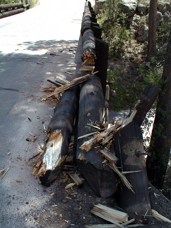 Photograph of vehicle damage caused to Pigtail Bridge on Highway 87.  Wood barriers are broken and splintered.