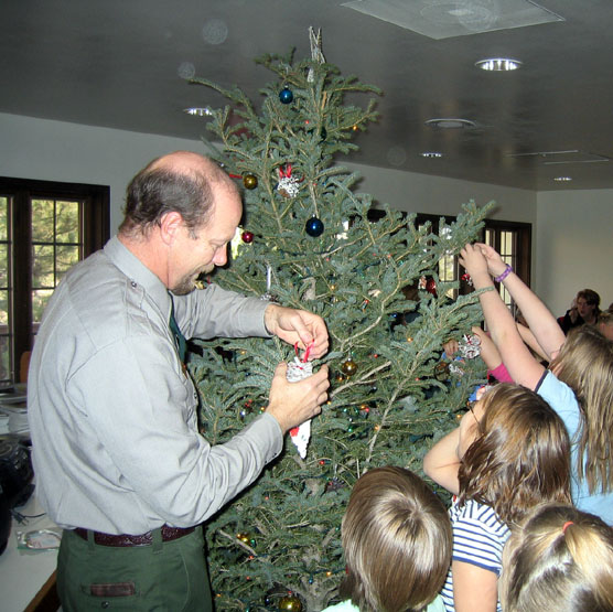 Park employee Dan Morford helping students decorate the visitor center tree.