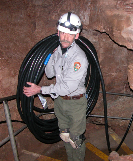 Maintenance Worker Mark Salmon carrying 135 feet of cable weighing 100 pounds for Wind Cave’s new lighting system.