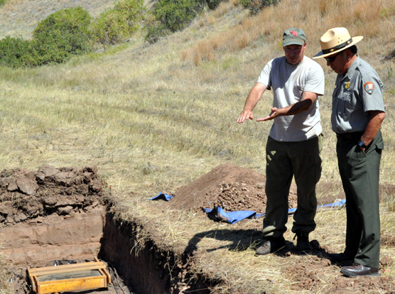NPS Archeologist Timothy Schilling stands next to a shallow tranch explaining to park superintendent Vidal Davila work occurring at the buffalo jump.