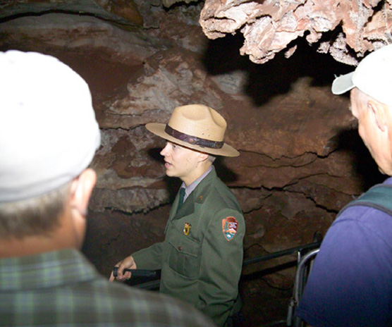 Uniformed male park ranger speaking with several visitors on a cave tour