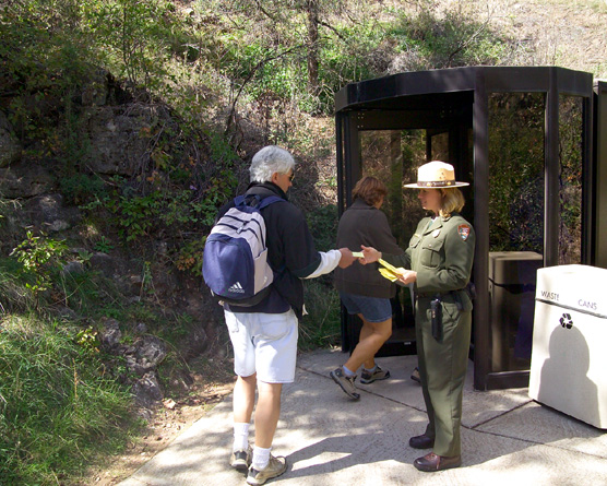 Uniformed park ranger collecting cave tour tickets from visitors as they enter revolving door entrance to Wind Cave