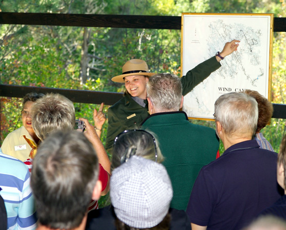 Ranger Tammy Wright points to a map of Wind Cave while standing in front of a tour.
