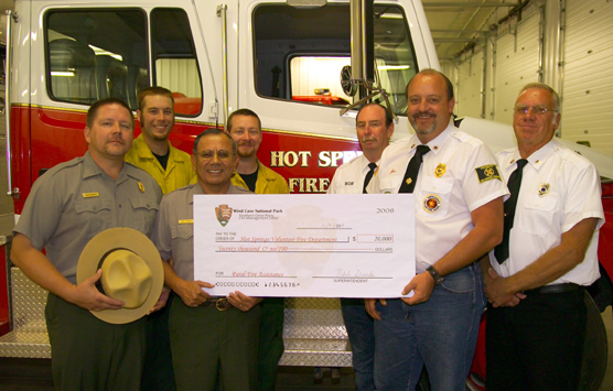 Employees from Wind Cave National Park present a symbolic check to Hot Springs Fire Department representatives.