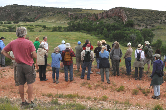 People standing listening to a park ranger with the buffalo jump in the distance.
