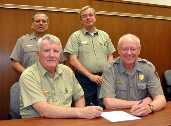 Two U.S. Forest Service rangers and two park superindentents signing agreement.