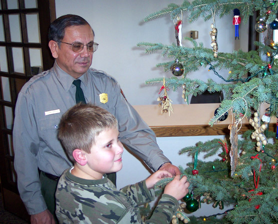 Superintendent Vidal Davila helps Matthew Horrocks decorate the park’s Christmas tree.