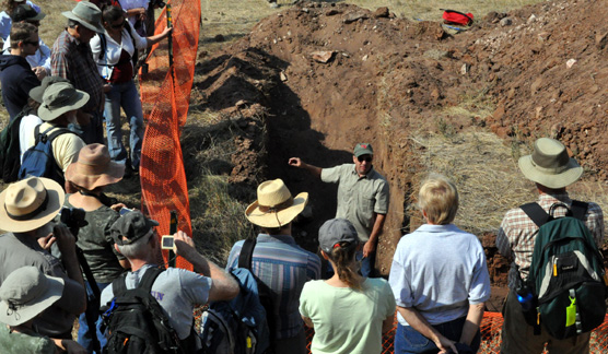 Archeologist Timothy Schilling stands in a trench surrounded by visitors as he describes the bones found in a trench at the Sanson Buffalo Jump.