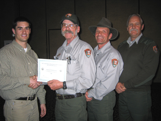Photo showing Bret Graves, Environmental Project Scientist, DENR, presenting the award and receiving it are (left to right) Steve White, Maintenance Mechanic, Mike Carder, Maintenance Worker, and Jeff Simmons, Mason.