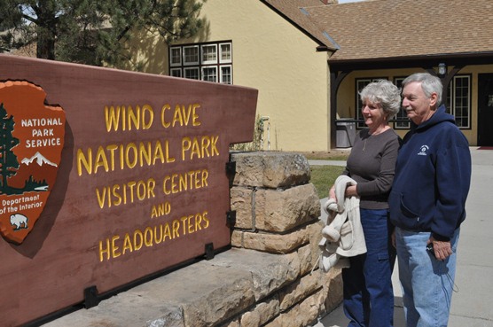 Mary and John Bertucci standing in front of the visitor entrance sign at Wind Cave National Park.